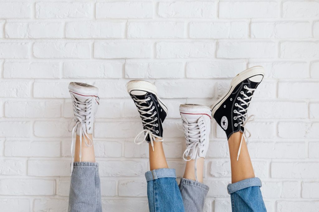 Stylish Converse sneakers against a white brick wall, showcasing casual fashion and youthful style.